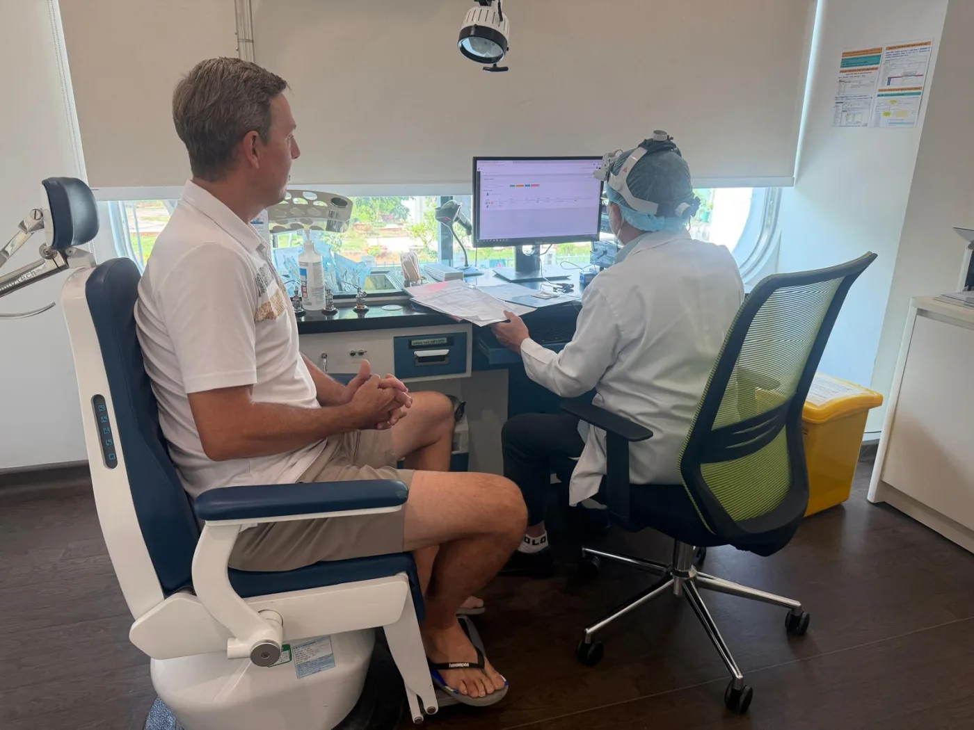 A patient seated beside a clinician who is reviewing documents at a desk